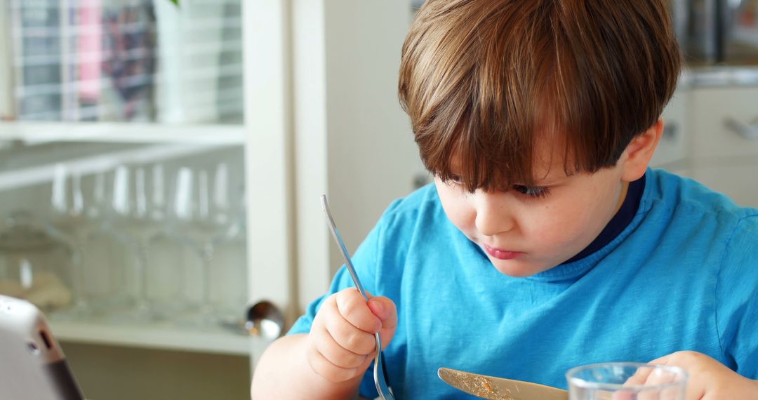 Little Boy Concentrating on Eating Breakfast at Home - Free Images, Stock Photos and Pictures on Pikwizard.com