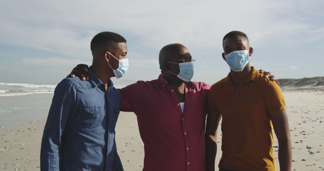 African american senior man with two adult sons in face mask embracing on beach - Free Images, Stock Photos and Pictures on Pikwizard.com