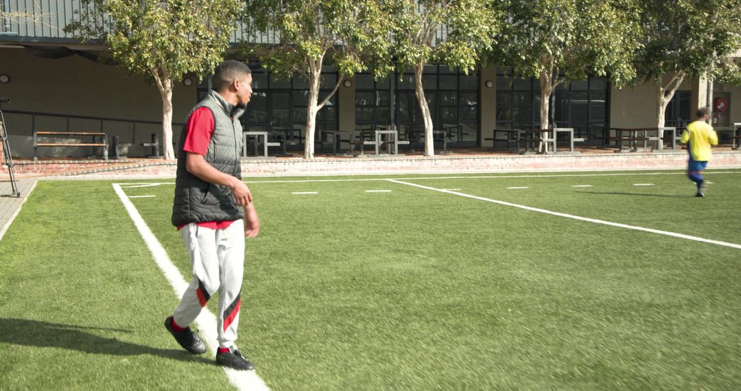 Athletic Man Walking on Soccer Field Enjoying Sunny Outdoors