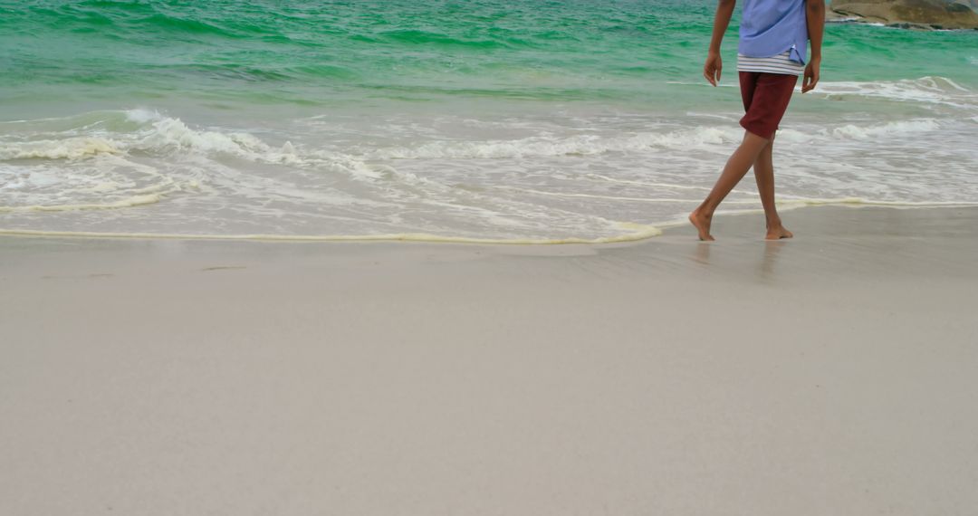 Man Walking Barefoot on Sandy Beach with Gentle Waves