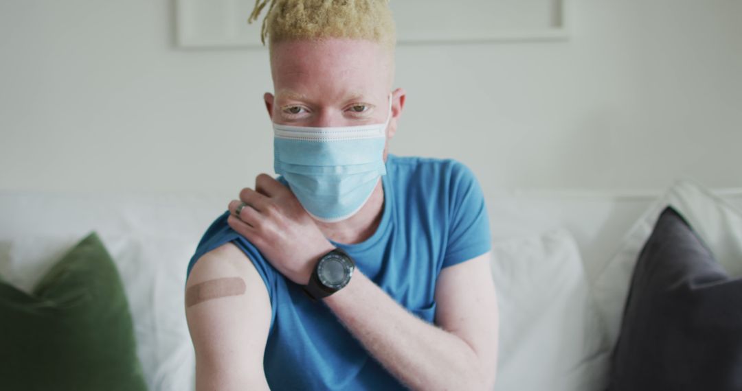 Man Wearing Mask Showing Vaccine Bandage on Arm Indoors - Free Images, Stock Photos and Pictures on Pikwizard.com