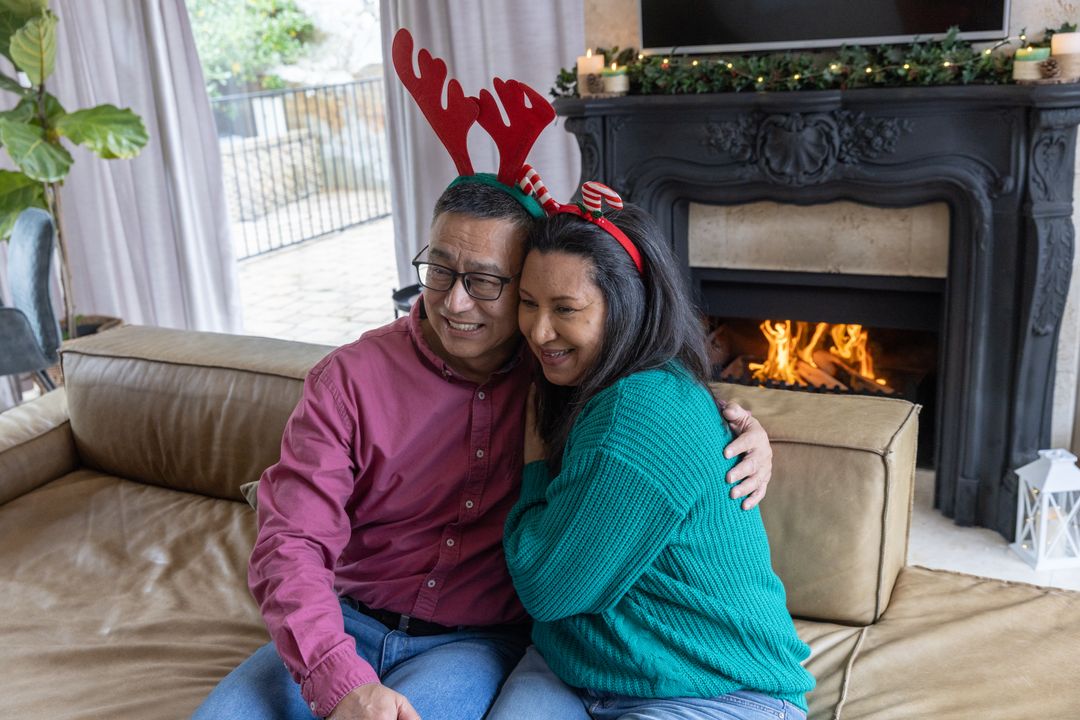 Couple Embracing by Fireplace with Reindeer Antlers During Holidays