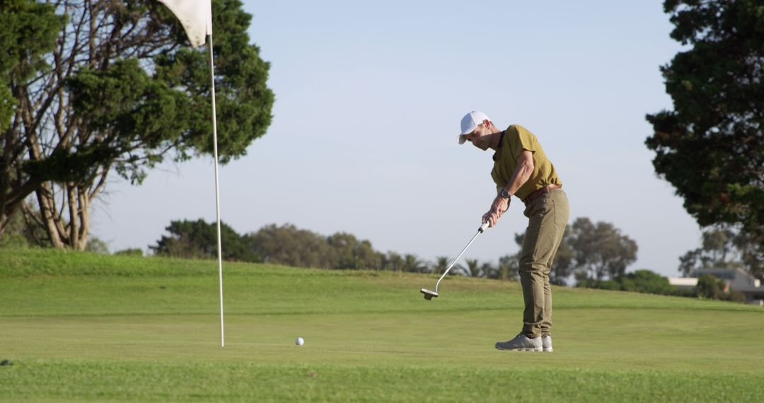 Man Playing Golf Focused on Putting on Sunny Day