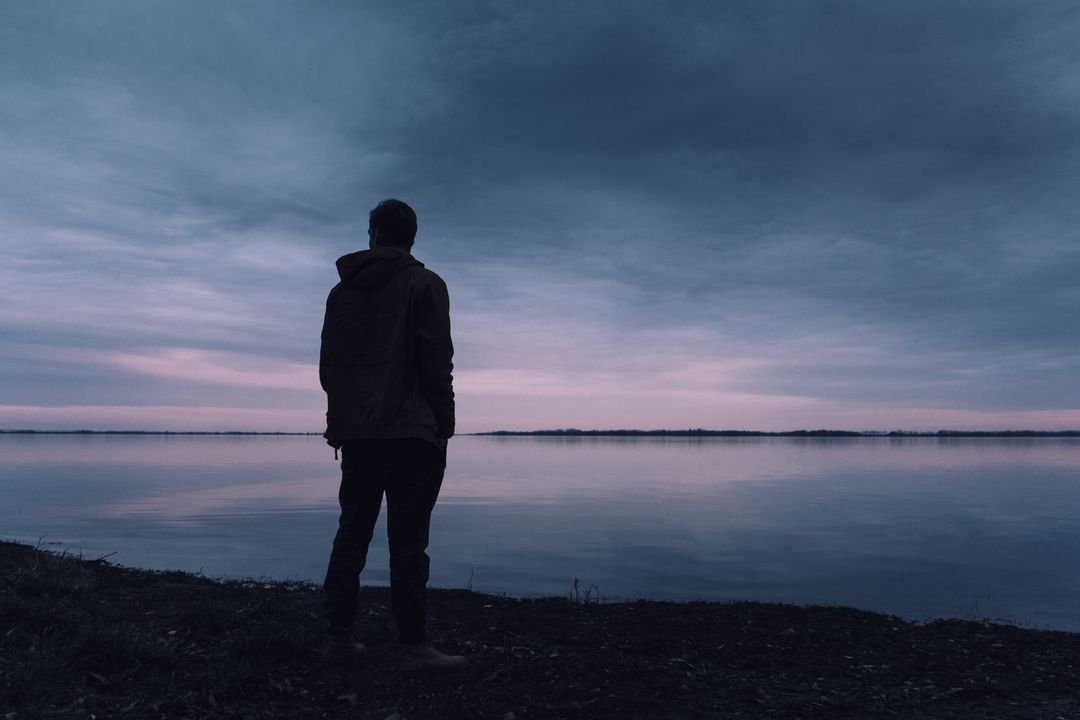 Silhouette of Person Gazing Over Serene Twilight Lake