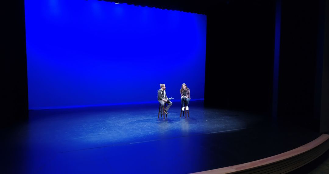 Stage Rehearsal with Blue Backdrop and Dramatic Lighting