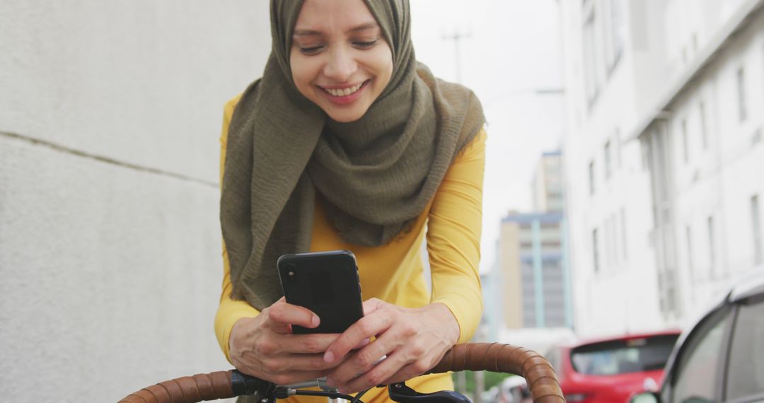 Muslim Woman in Hijab Using Smartphone While Cycling in Urban Area - Free Images, Stock Photos and Pictures on Pikwizard.com