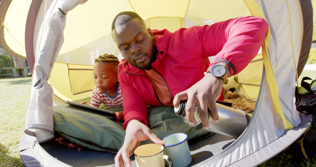 Father and Son Camping with Tablet and Thermos in Sunny Garden Tent - Free Images, Stock Photos and Pictures on Pikwizard.com