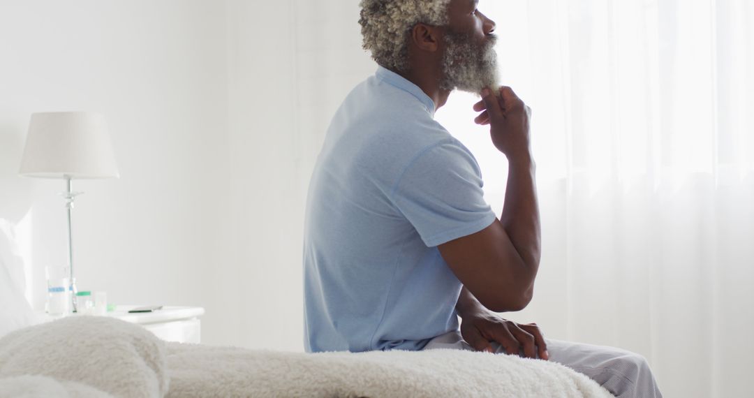 Pensive Elderly Man Sitting on Bed in White Room - Free Images, Stock Photos and Pictures on Pikwizard.com