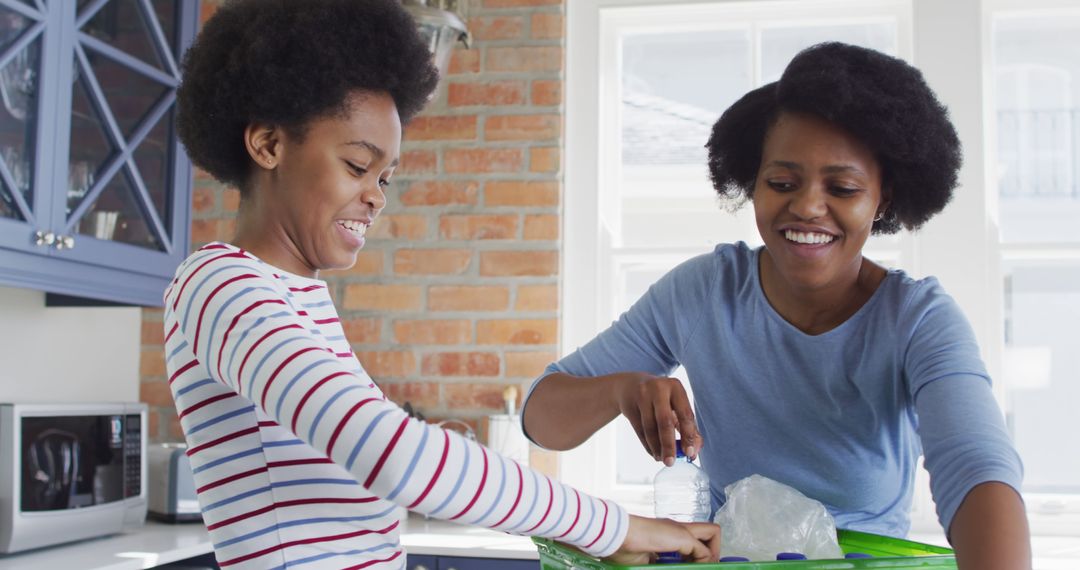 Mother and Daughter Smiling While Recycling in Kitchen