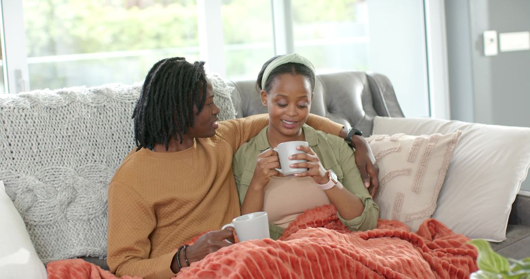 Cozy African American Couple Cuddling on Sofa Drinking Coffee Under Rust Orange Throw