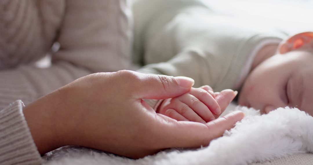 Mother Holding Infant's Hand in Cozy Nursery Setting