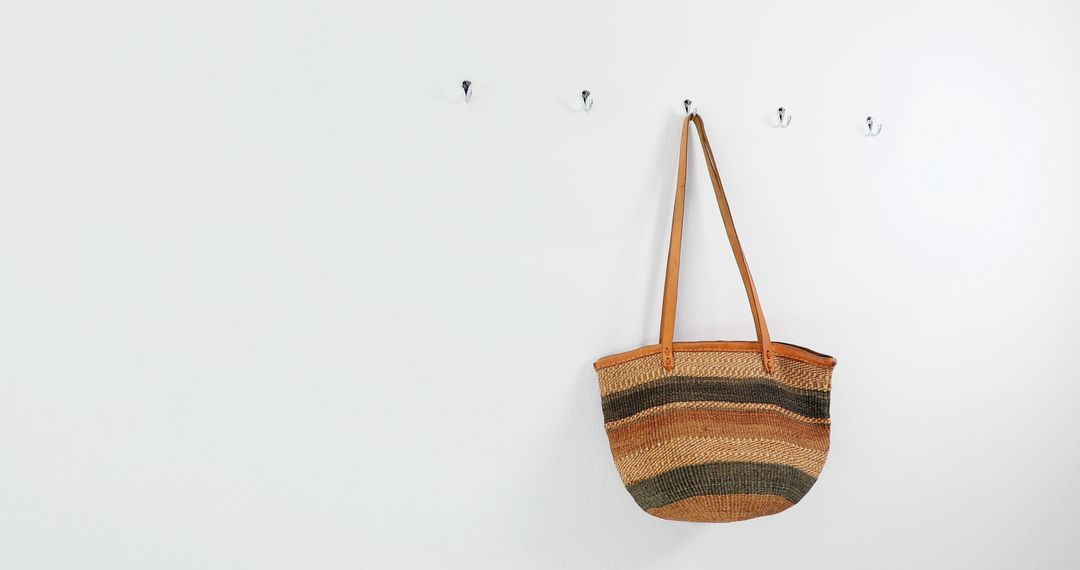 A woven basket hangs on a hook against a clean, white wall, with copy space - Free Images, Stock Photos and Pictures on Pikwizard.com