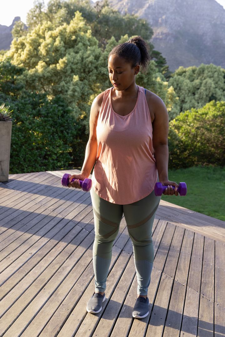 Woman Exercising with Dumbbells on Deck in Scenic Nature