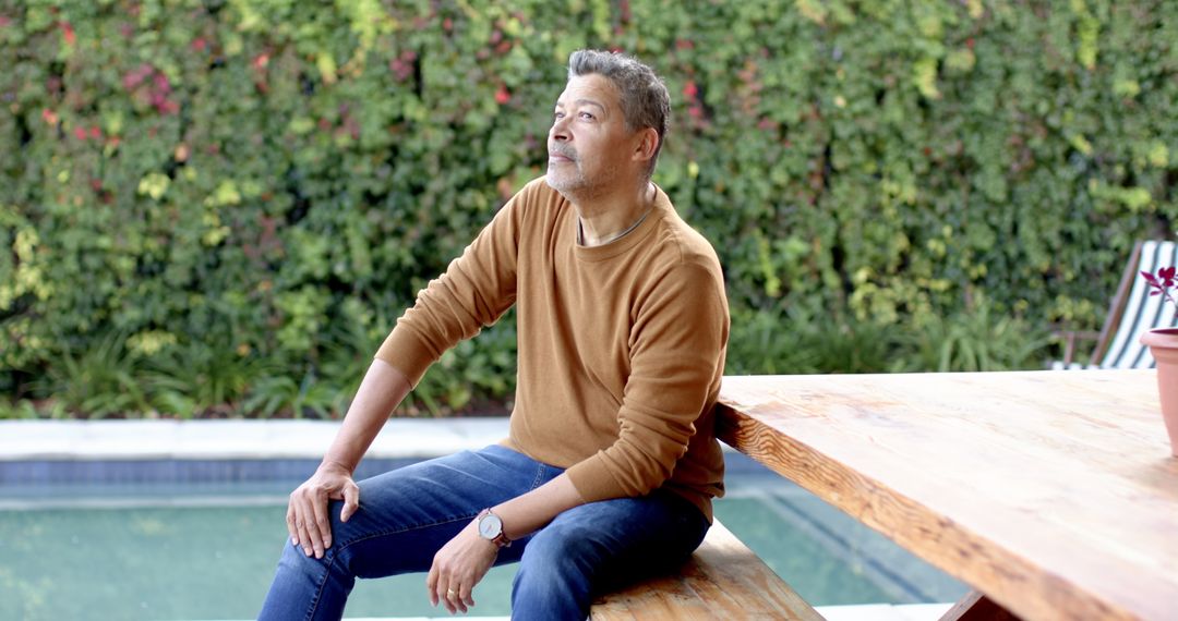 Senior Man Relaxing Beside Garden Pool Gazing Thoughtfully