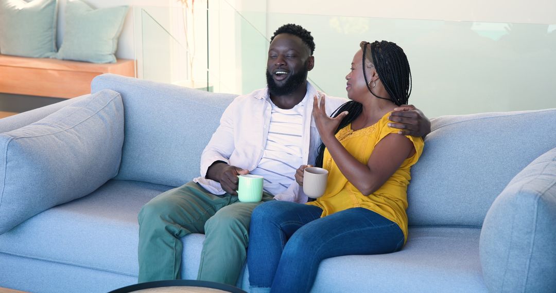 Relaxed Couple Enjoying Coffee and Laughter on Comfortable Sofa