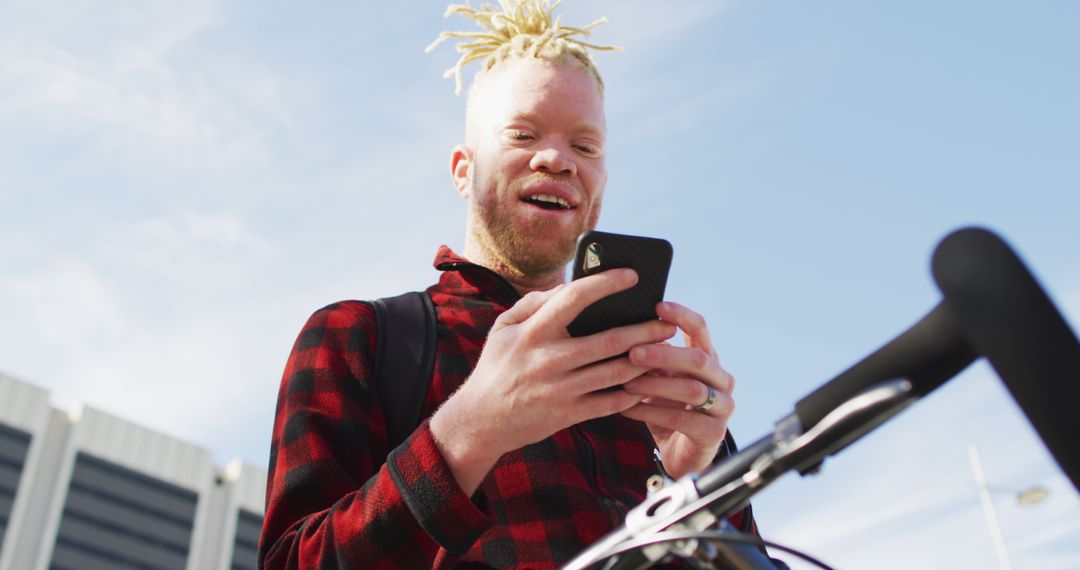 Albino man smiling while texting on a phone outdoors - Free Images, Stock Photos and Pictures on Pikwizard.com