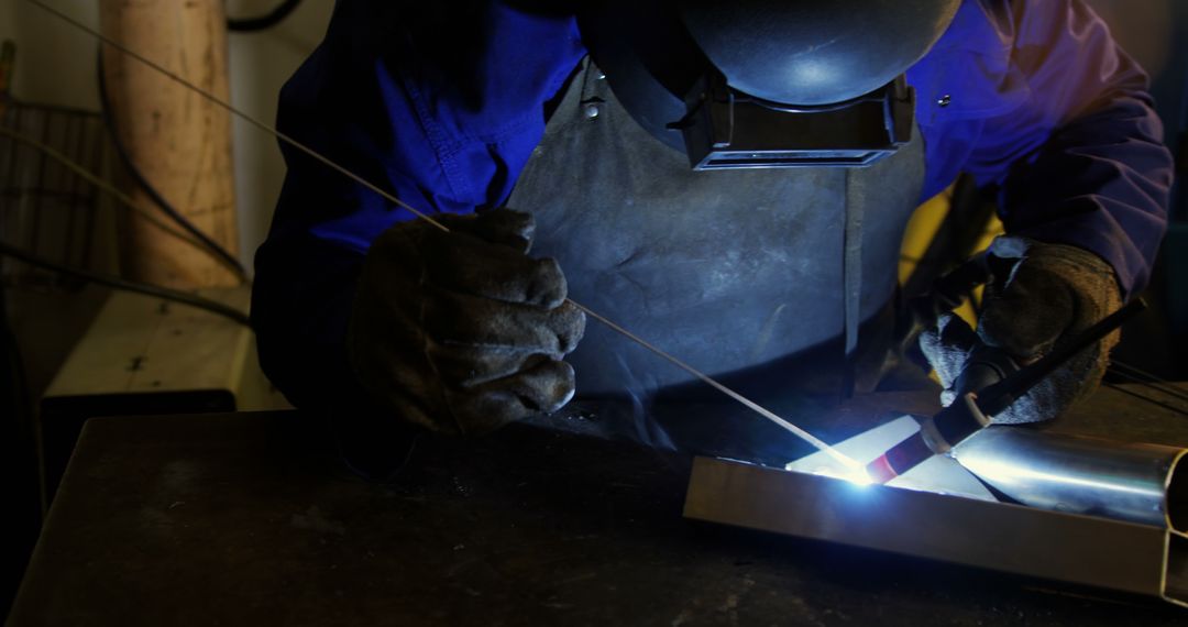 Professional Welder Working on Metal Piece in Dimly Lit Workshop - Free Images, Stock Photos and Pictures on Pikwizard.com