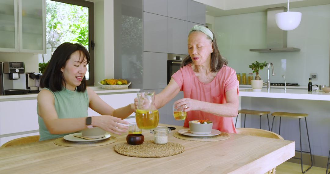 Mother and Daughter Enjoying Juice Together in Modern Kitchen