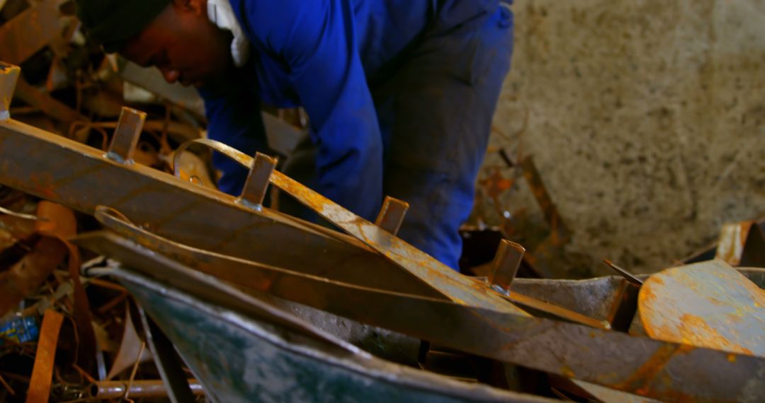 Worker putting metal in wheelbarrow in foundry workshop - Free Images, Stock Photos and Pictures on Pikwizard.com