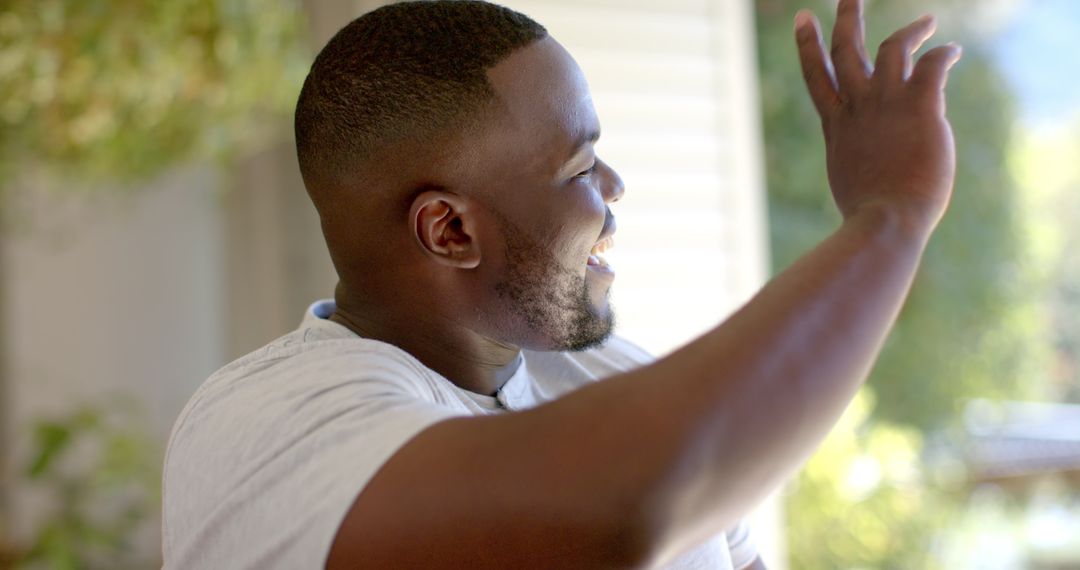 Smiling Man Waving to Friends, Enjoying Relaxed Time at Home