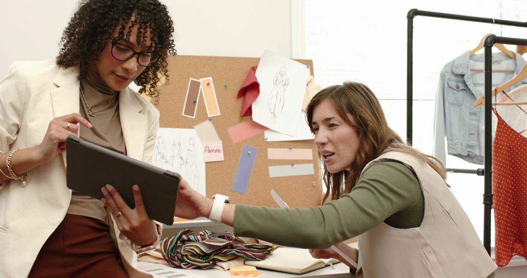 Fashion Designers Collaborating Over Tablet and Moodboard, Reviewing Fabric Sketches