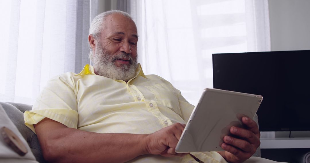 Senior Man Engaging with Digital Technology on Tablet at Home