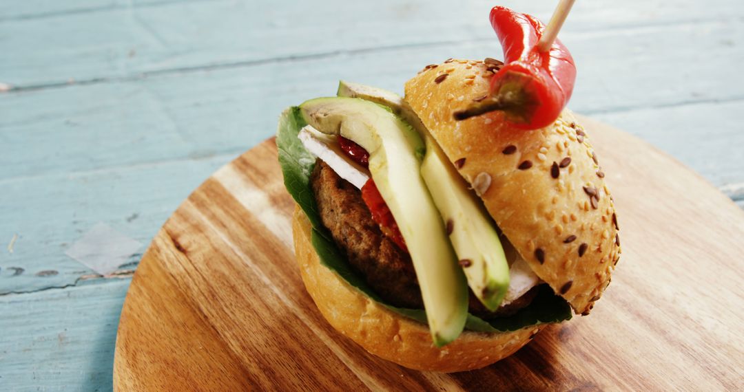 Gourmet burger with avocado, chili pepper, and sesame bun on rustic wooden board - Free Images, Stock Photos and Pictures on Pikwizard.com