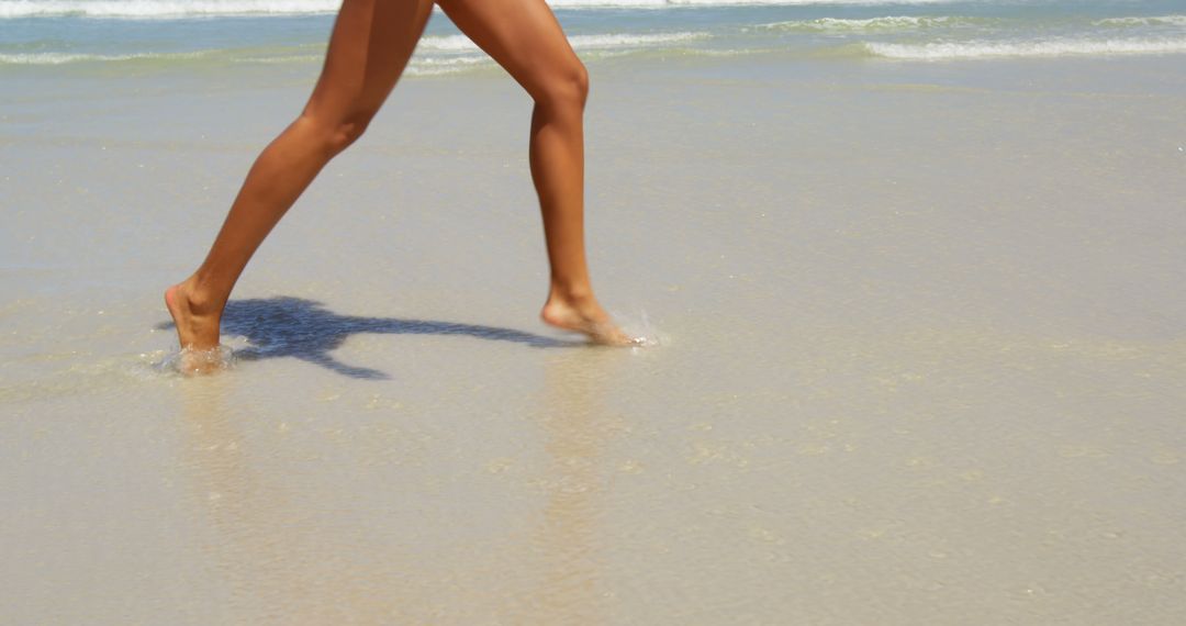 Woman Walking Along Sandy Beach with Gentle Waves - Free Images, Stock Photos and Pictures on Pikwizard.com