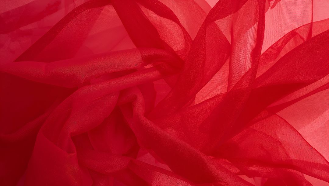 Crimson organza flowing in translucent layers with backlit folds for luxe texture
