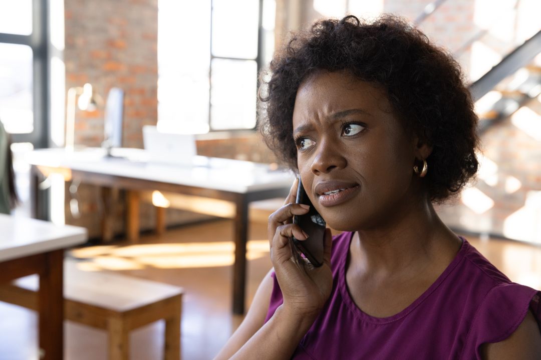 Professional Woman Expressing Concern While Talking on Smartphone in Office