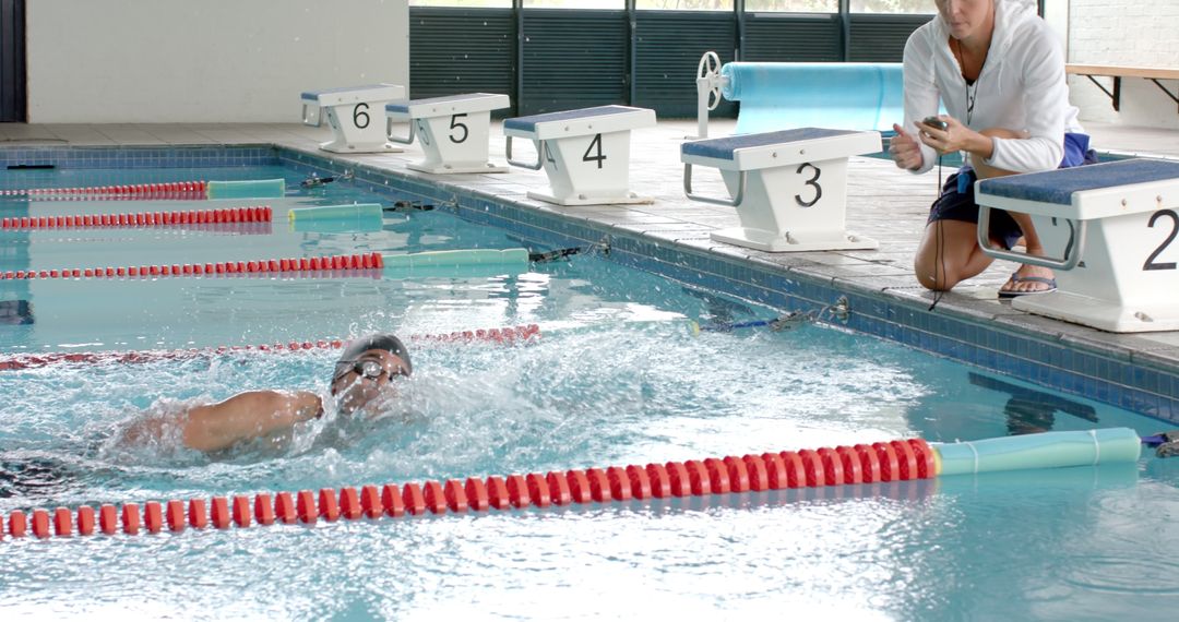 Coach Monitoring Swimmer Training at Indoor Pool in Slow Motion