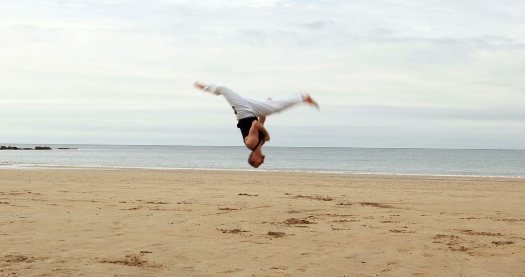 Man Performing Backflip on Sandy Beach - Free Images, Stock Photos and Pictures on Pikwizard.com