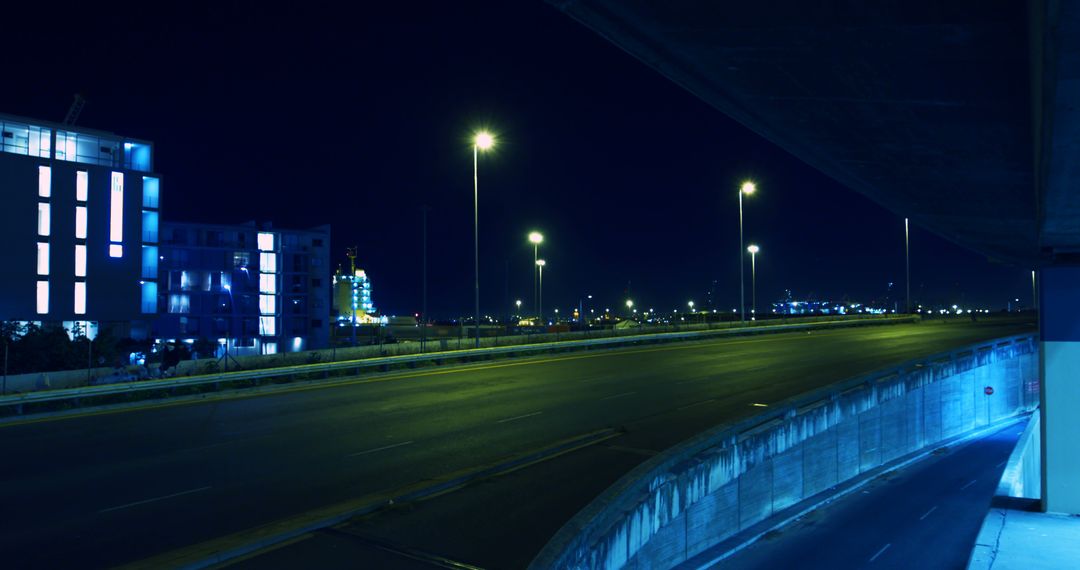 Empty Highway at Night with Illuminated Buildings and Street Lights - Free Images, Stock Photos and Pictures on Pikwizard.com