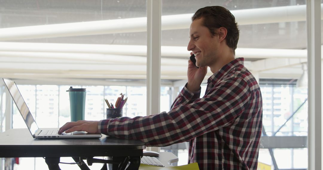 Man Talking on Smartphone at Standing Desk in Bright Office - Free Images, Stock Photos and Pictures on Pikwizard.com