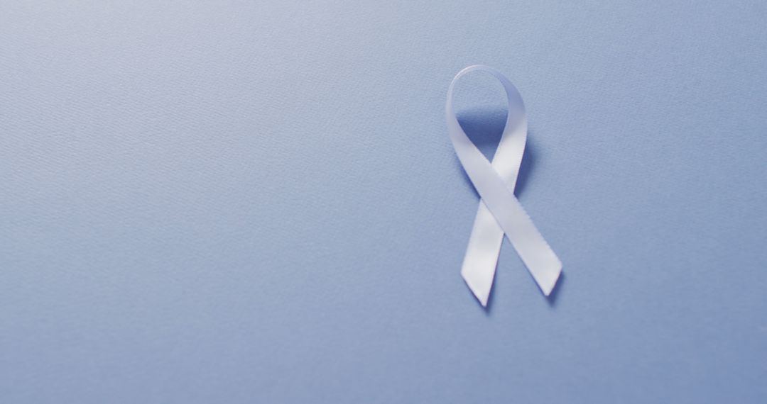 Image of pale blue prostate cancer ribbon on blue background - Free Images, Stock Photos and Pictures on Pikwizard.com
