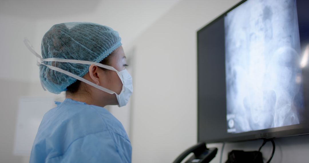 Healthcare professional analyzing X-ray scan wearing surgical mask in hospital - Free Images, Stock Photos and Pictures on Pikwizard.com