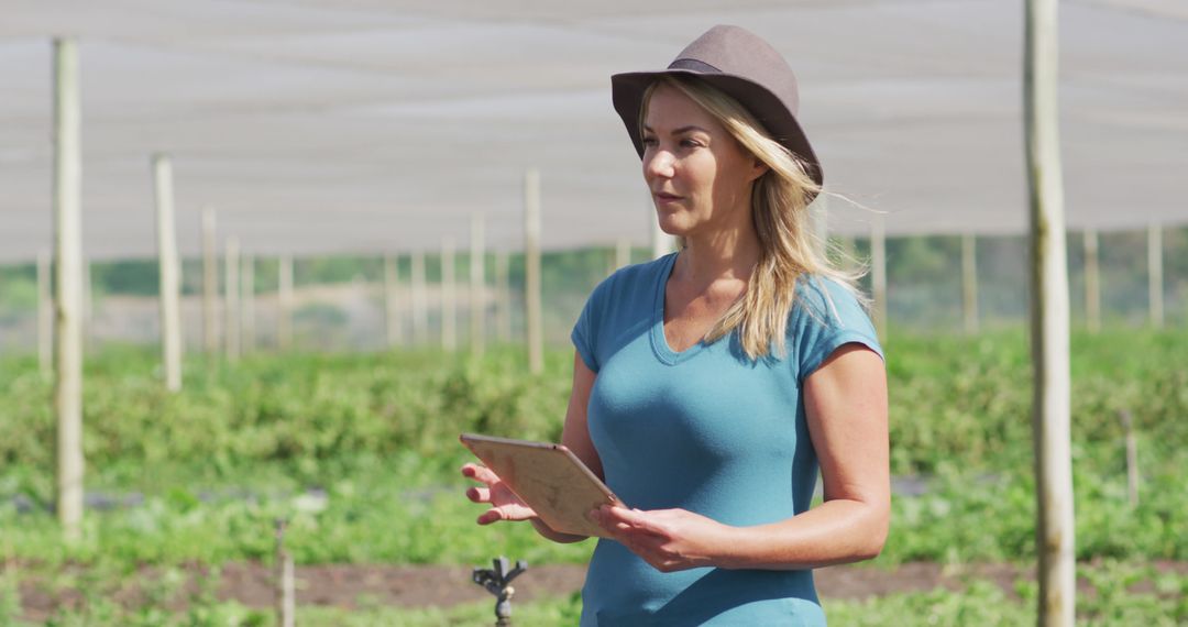 Woman Using Tablet in Modern Organic Farm Greenhouse