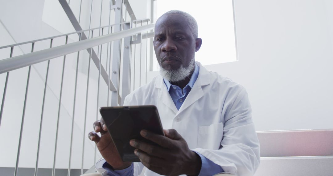 African American Doctor Using Digital Tablet on Hospital Staircase - Free Images, Stock Photos and Pictures on Pikwizard.com