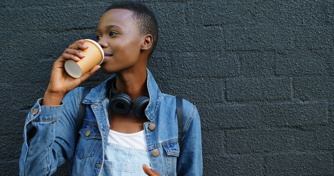 Young African-American Woman Drinking Coffee Against Black Brick Wall - Free Images, Stock Photos and Pictures on Pikwizard.com