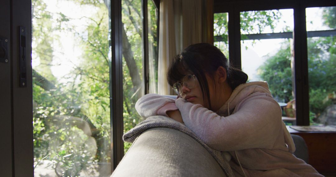 Pensive Woman Contemplating by Window in a Sunlit Room - Free Images, Stock Photos and Pictures on Pikwizard.com