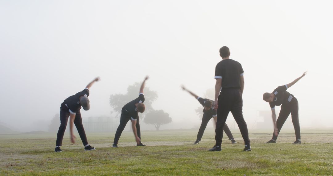 Group of Athletes Stretching in Morning Fog with Coach