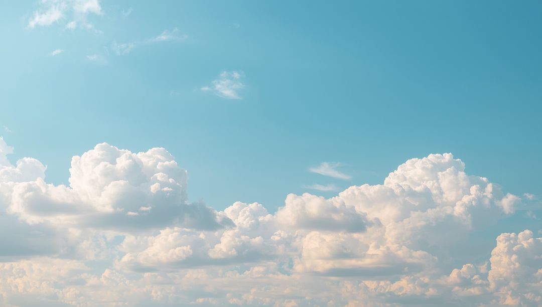 Fluffy Cumulus Clouds Against Clear Blue Sky