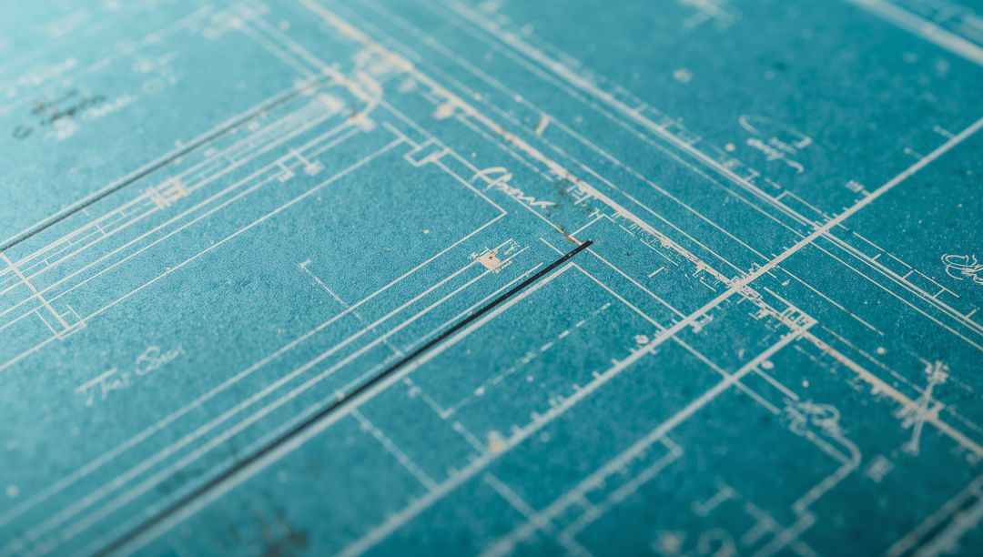 Teal blueprint revealing architectural floorplan with metal ruler, scale and annotations