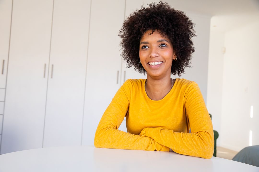 Smiling Woman in Bright Top Sitting at Dining Table