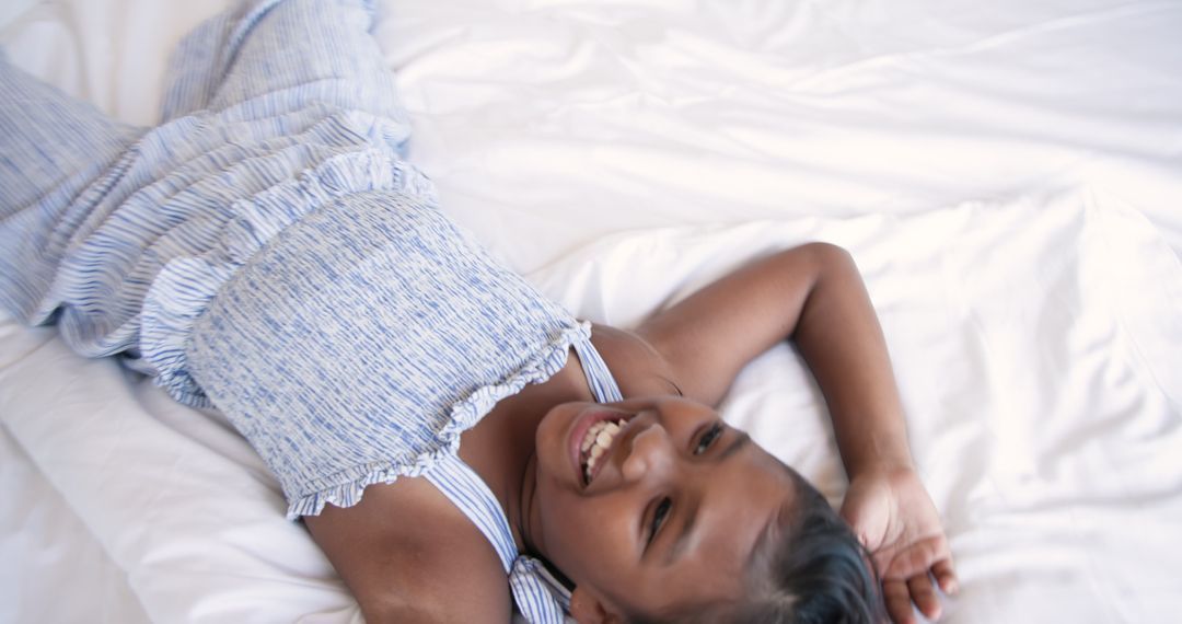 Smiling Girl Relaxing on Cozy White Bedding
