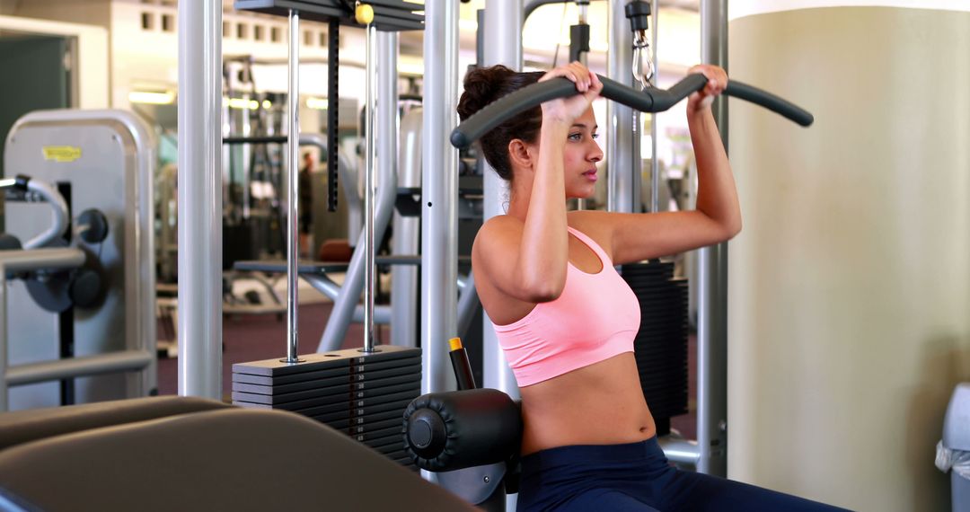 Focused Woman Exercising on Weight Machine in Modern Gym - Free Images, Stock Photos and Pictures on Pikwizard.com