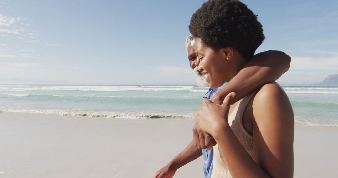 Happy african american couple walking and embracing on sunny beach - Free Images, Stock Photos and Pictures on Pikwizard.com