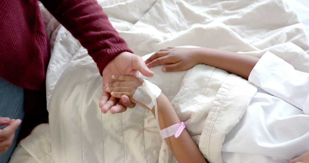 Midsection of african american girl patient and her mother holding hands in bed in hospital room - Free Images, Stock Photos and Pictures on Pikwizard.com