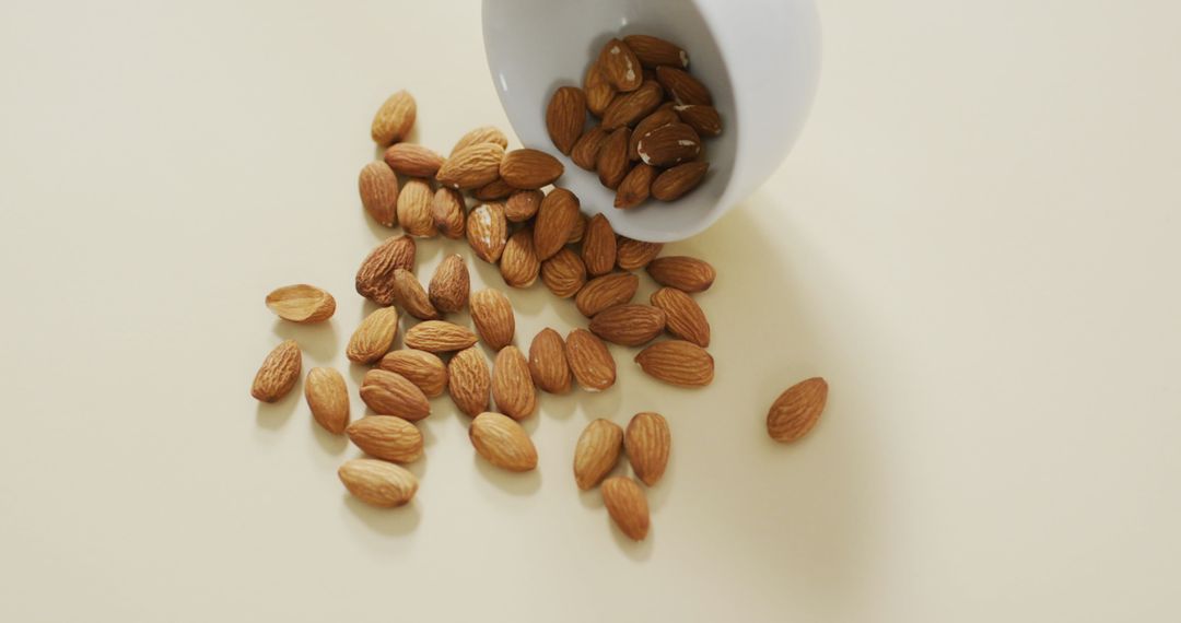 Almonds Spilling from Bowl on Minimalist White Background
