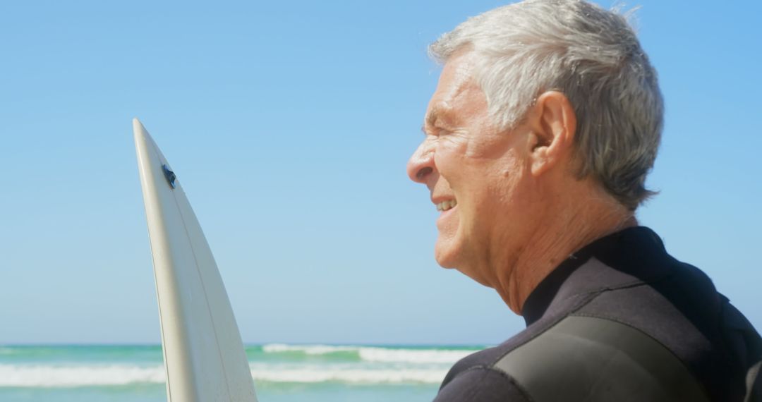 Senior Man with Surfboard Enjoying Beach View